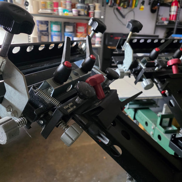 Close up of the screen clamps and micro-registration knobs on the press print heads at RVA Threads screen printing, Virginia