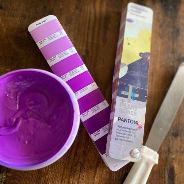 Purple ink mixed to match a Pantone swatch, with the spatula and swatch book at RVA Threads screen printing, Virginia