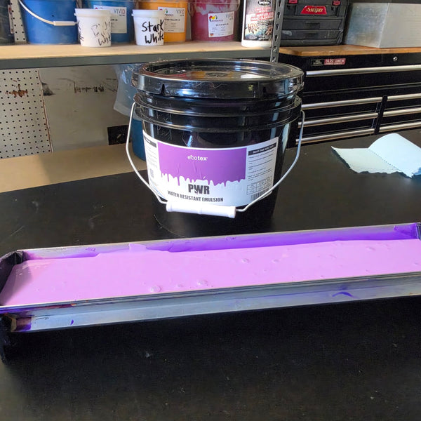 Scoop coater filled with purple photo emulsion beside the emulsion bucket, ready to coat a screen at RVA Threads screen printing, Virginia