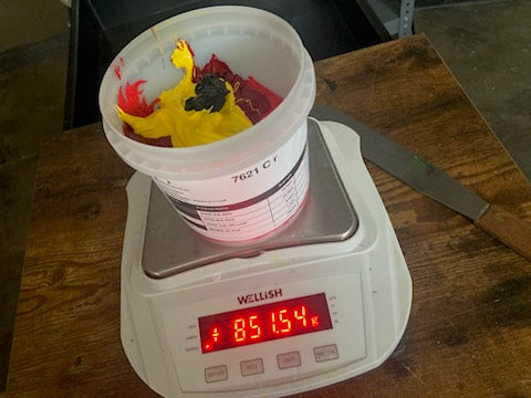 Red, yellow and black ink in a cup on a digital scale while mixing a custom color at RVA Threads screen printing, Virginia