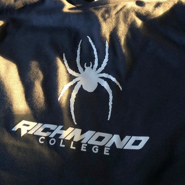Richmond College spider logo in white ink on a navy tee, laid flat at RVA Threads screen printing, Virginia