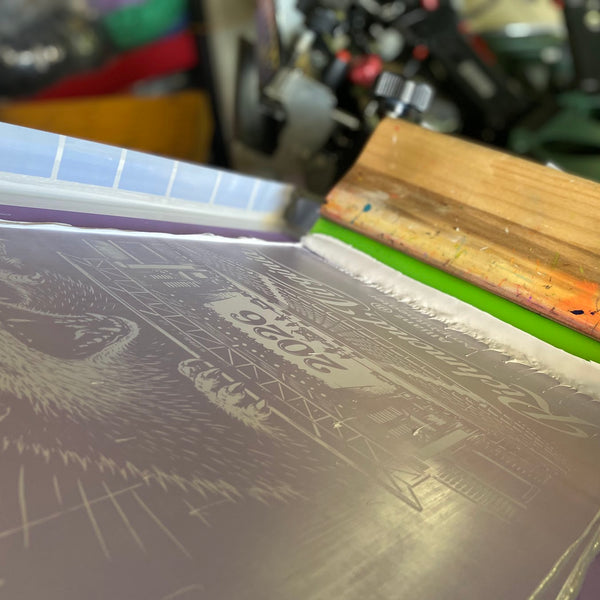 Richmond opossum design screen with white ink and the squeegee on the press at RVA Threads screen printing, Virginia