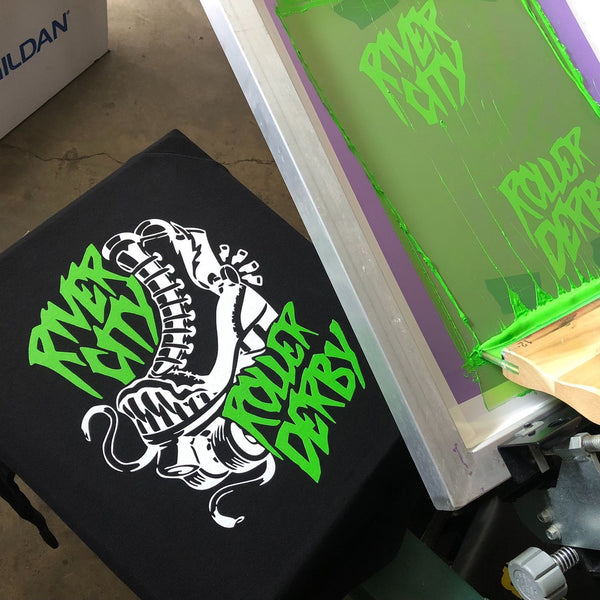 River City Roller Derby skate design in neon green and white ink on a black tee, screen raised at RVA Threads screen printing, Virginia