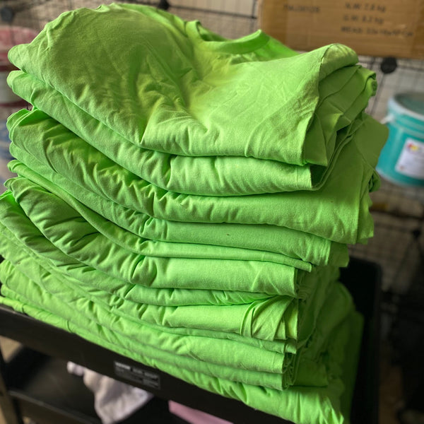 Printed safety green volunteer tees folded and stacked after printing at RVA Threads screen printing, Virginia