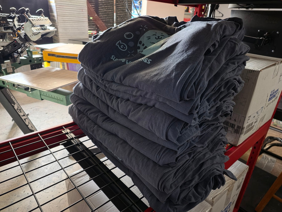 Sleeping With Da Fishes seal tees in light blue on Denim Comfort Colors 1717, folded and stacked at RVA Threads screen printing, Virginia