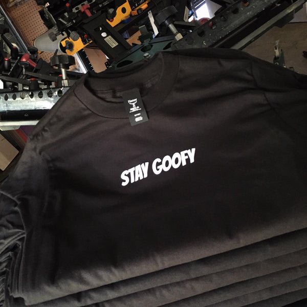 Stay Goofy lettering in white ink on black tees, folded and stacked at RVA Threads screen printing, Virginia