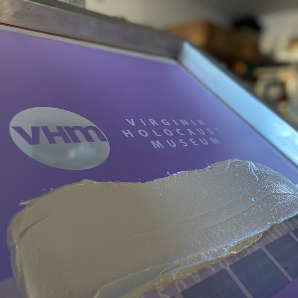 Virginia Holocaust Museum logo screen with ink and the squeegee on the press at RVA Threads screen printing, Virginia