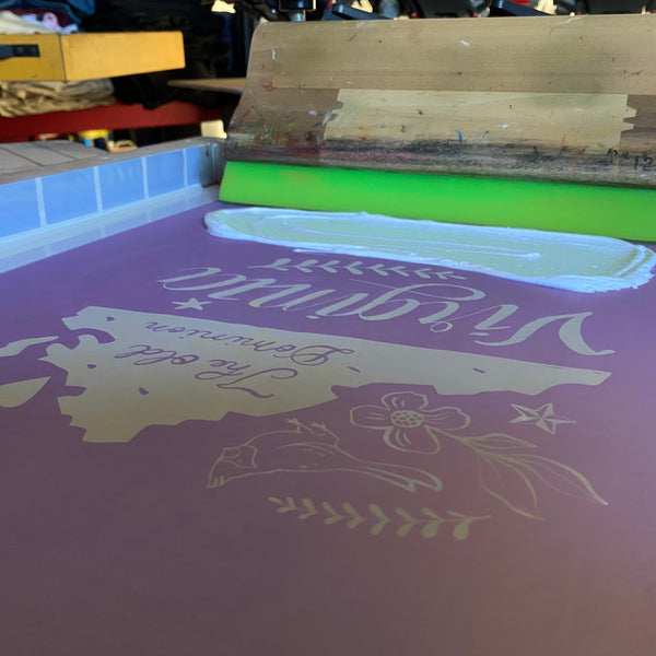 Virginia map and flowers screen with white ink and the squeegee on the press at RVA Threads screen printing, Virginia