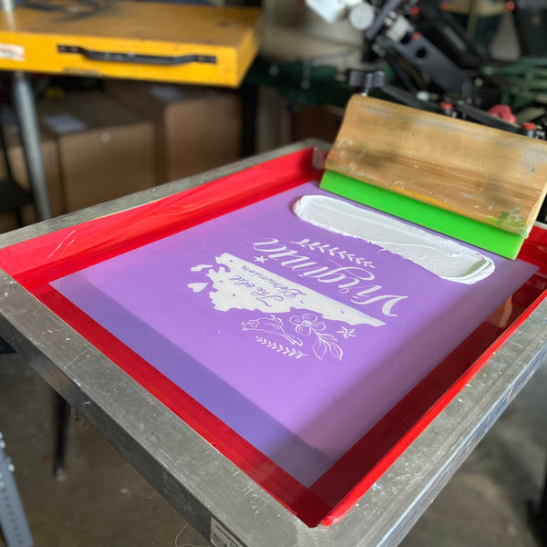 Virginia design screen with white ink and a squeegee on the press at RVA Threads screen printing, Virginia