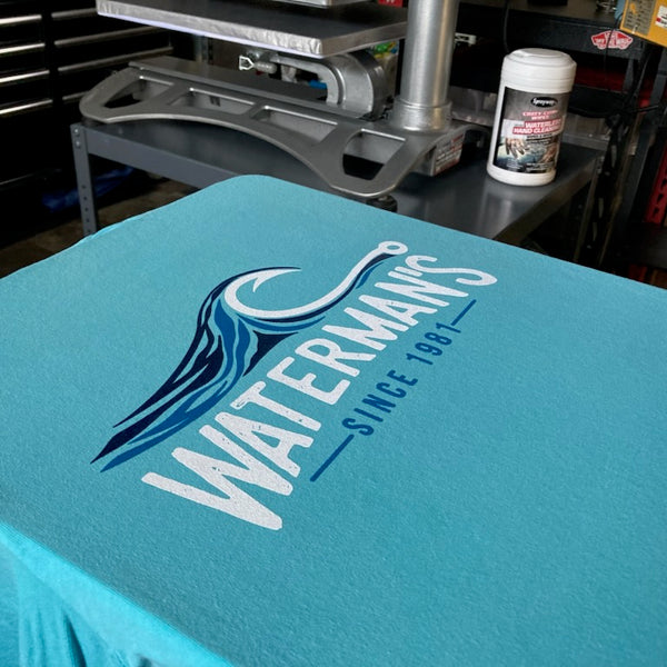 Waterman's wave logo in navy and white ink on a chalky blue tee on the pallet at RVA Threads screen printing, Virginia