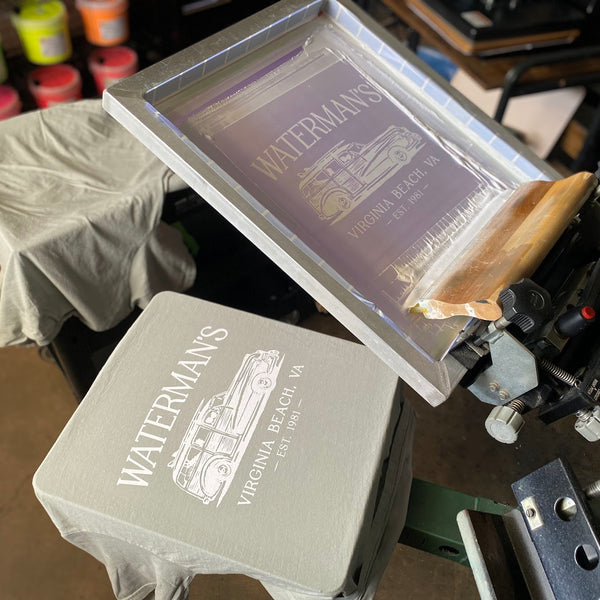 Waterman's woody wagon screen raised over a printed gray tee on the press at RVA Threads screen printing, Virginia