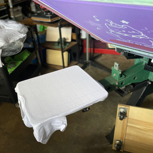White tee loaded on the press pallet under a raised screen, ready to print at RVA Threads screen printing, Virginia
